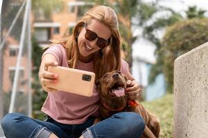 een vrouw duurt een selfie met haar hond buitenshuis. foto