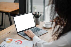 detailopname terug visie van een bedrijf vrouw werken in de kantoor typen, op zoek Bij de scherm. kantoor arbeider gebruik makend van een notitieboekje computer. foto