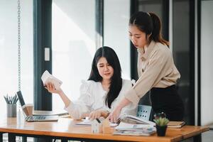 twee vrouw echt landgoed professionals bespreken project details met een model- huis Aan de tafel, symboliseert project planning en teamwerk. foto