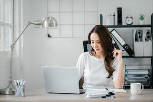 jong vrouw werken Aan haar laptop in een goed georganiseerd huis kantoor omgeving, exposeren concentratie en professionaliteit. foto