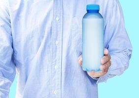 Mens slijtage blauw overhemd hand- houden mockup blauw doorzichtig plastic drinken water fles geïsoleerd Aan blauw achtergrond foto
