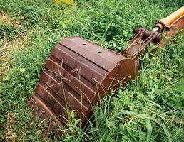 de graafmachine emmer was onverzorgd en roestig aan het liegen tussen de gras foto