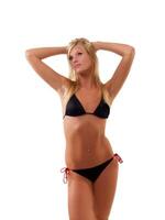 jong mager blond vrouw in zwart bikini staand foto