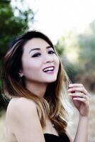 Aziatisch Amerikaans vrouw buitenshuis in kaal schouder jurk glimlachen foto