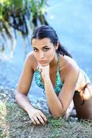 jong vrouw Aan rivier- bank in bikini portret foto