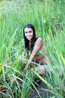 jong vrouw in bikini te midden van groen gras foto