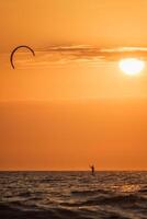 kiteboarden kitesurfen kiteboarder kitesurfer vliegers silhouet in de oceaan Aan zonsondergang foto