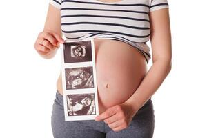 zwanger vrouw staand en Holding haar echografie baby scannen foto