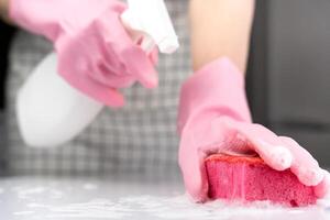 een huisvrouw spatten reiniger op haar spons. huis schoonmaak concept. detailopname. selectief focus. foto