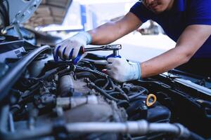 detailopname van een auto monteur repareren een auto in een garage, auto veiligheid controleren de motor in de garage, reparatie onderhoud concept. foto