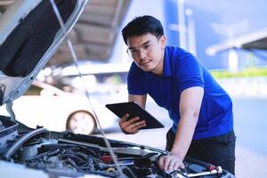 Aziatisch monteur controle de veiligheid van een auto in een auto zorg centrum. onderhoud van beschadigd onderdelen in de garage. onderhoud. reparatie onderhoud concept. foto