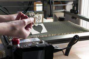 laser gravure en snijden, vrouw Holding een voorbeeld van een besnoeiing uit houten hart foto