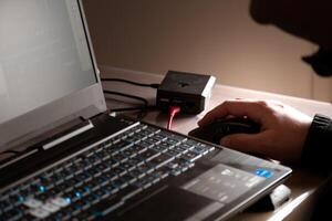 dichtbij omhoog van man's hand- gebruik makend van draadloze muis, framboos pi en laptop computer met blauw verlicht toetsenbord foto