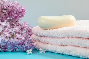 handdoek, room en zeep Aan achtergrond van delicaat lila bloemen. foto