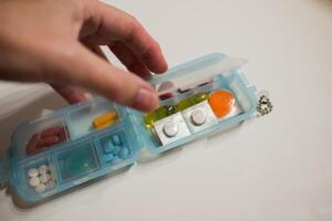 vrouw hand- opening een eerste steun reizen doos met pillen foto