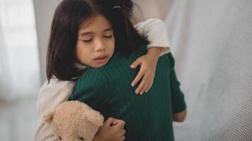 een vrouw is knuffelen een kind en een teddy beer foto