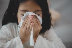 een ongezond kind blazen hun neus- in een zakdoek, een kind lijden van rennen neus- of niezen, een meisje vangen een verkoudheid wanneer de seizoen Wijzigen, een kinderjaren afvegen neus- met een zakdoek foto