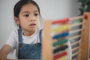 schattig Aziatisch kind meisje aan het leren naar tellen gebruik makend van een telraam in de klas Bij kleuterschool. foto