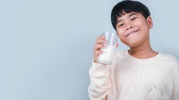 concept van gelukkig mooi zo voeding, portret van een weinig jong knap kind jongen in room kleur shirt, houden drinken melk doos model, geïsoleerd Aan wit achtergrond. foto