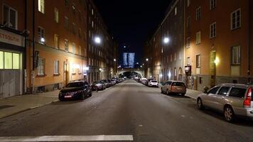 een straat in de centrum van Stockholm gedurende de nacht. van een afstand u kan zien de lichten van een modern gebouw. foto