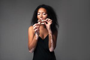 mooi Afrikaanse meisje met vitiligo in de studio aan het eten zwart en wit chocola. foto