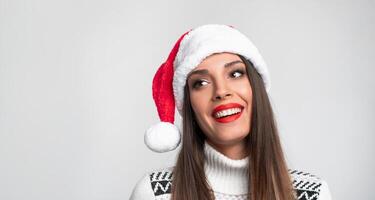 dichtbij omhoog portret mooi Kaukasisch vrouw in rood de kerstman hoed Aan wit studio achtergrond. Kerstmis en nieuw jaar vakantie concept. foto