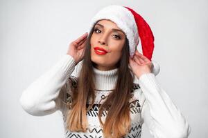 dichtbij omhoog portret mooi Kaukasisch vrouw in rood de kerstman hoed Aan wit studio achtergrond. Kerstmis en nieuw jaar vakantie concept. foto