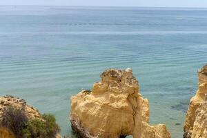 de rotsachtig kliffen van dal Doen olijfgroen strand in armacao de pera, Portugal foto