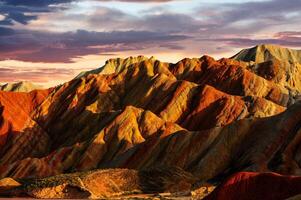 verbazingwekkend landschap van China bergen en blauw lucht achtergrond in zonsondergang. zhangye danxia nationaal geopark, Gansu, China. kleurrijk landschap, regenboog heuvels, ongebruikelijk gekleurde rotsen, zandsteen erosie foto