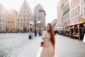 een bruid in een bruiloft jurk met lang haar- en een drinken fles in de oud stad- van Wroclaw. bruiloft foto schieten in de centrum van een oud Pools stad.wroclaw, Polen