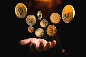 gouden bitcoin munt bij de hand op donkere achtergrond foto