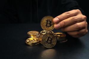 een gouden bitcoin in de hand van een mysterieuze man. foto