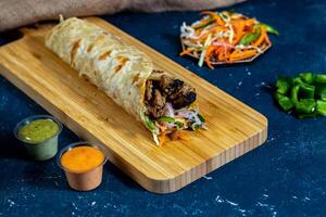 kip reshmi tikka shoarma inpakken met salade dip en saus geïsoleerd houten bord kant visie van Fast food foto