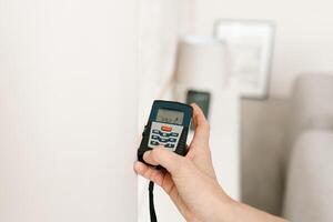 laser afstandsmeter in de handen van een vrouw. een ingenieur Holding een laser afstandsmeter. dichtbij omhoog van een meten apparaat in een huis. ontwerper gebruik makend van een elektronisch afstandsmeter in een kamer foto