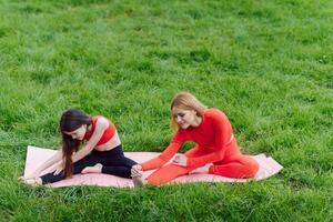 schattig klein dochter en moeder Doen oefeningen, fitheid, yoga in ochtend- park foto