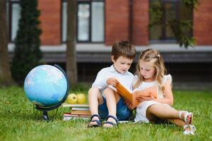 twee leerlingen van primair school. jongen en meisje met school- Tassen achter de rug. begin van school- lessen. warm dag van val. terug naar school. weinig eerste klassers. foto