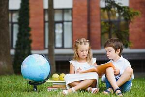 twee leerlingen van primair school. jongen en meisje met school- Tassen achter de rug. begin van school- lessen. warm dag van val. terug naar school. weinig eerste klassers. foto