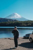 vrouw toerist genieten met fuji berg Bij meer saiko, gelukkig reiziger bezienswaardigheden bekijken monteren fuji en weg reis fuji vijf meren. mijlpaal voor toeristen attractie. Japan reis, bestemming en vakantie foto