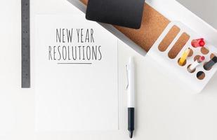 nieuwjaarsresoluties 2020 papieren notitie over moderne kantoorbenodigdheden op witte tafel. potlood, notitieblok, liniaal, pen en potlooddoos met plant foto