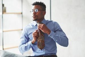 het bevestigen van de stropdas. foto van zwarte stijlvolle man die kleding draagt en zich voorbereidt op het werk