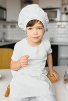 weinig jongen in keuken.schattig jongen draagt een chef hoed en schort. foto