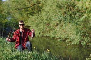 Mens ontspannende en visvangst door oever van het meer. weekends gemaakt voor vissen. visser mannelijk hobby. meester lokaas. houden kalmte en vis Aan. fishman gehaakt spinnen in de rivier- aan het wachten groot vis. vent vlieg visvangst foto