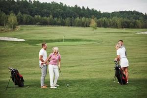 groep stijlvolle vrienden op de golfbaan leren een nieuw spel te spelen