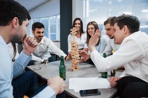 als kinderen weer. succesvolle deal vieren. jonge kantoormedewerkers zitten bij de tafel met alcohol foto