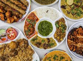 sindhi niet groente thali met aloo Keema, kip korma, kerrie Pakora, rijst, biryani, grillen, jaleem daal en chutney geserveerd in bord geïsoleerd Aan tafel top visie van Indisch en Pakistaans pittig voedsel foto