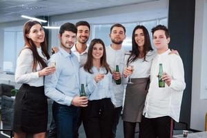 een goede tijd hebben. foto van een jong team in klassieke kleding met drankjes in het moderne, goed verlichte kantoor