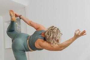 een 50 jaar oud vrouw doet yoga Bij huis foto