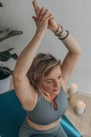 een 50 jaar oud vrouw doet yoga Bij huis foto