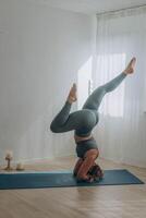 een 50 jaar oud vrouw doet yoga Bij huis foto