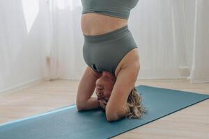 een 50 jaar oud vrouw doet yoga Bij huis foto